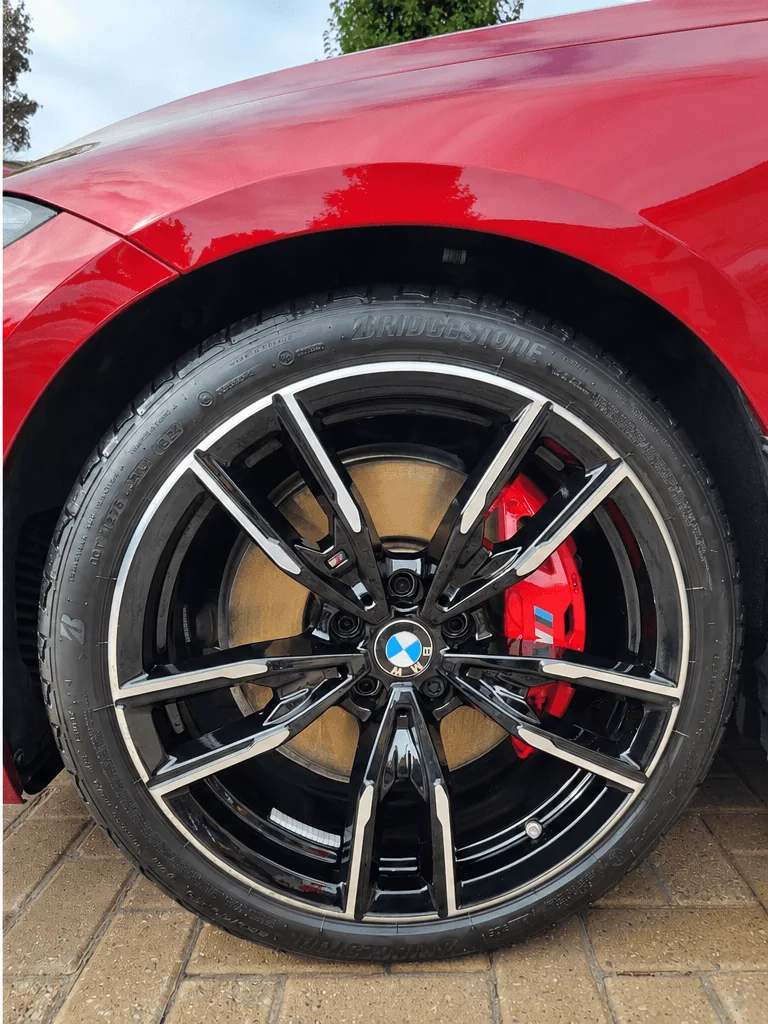 After: the same BMW M440i wheel clean, with glossy black tire dressing