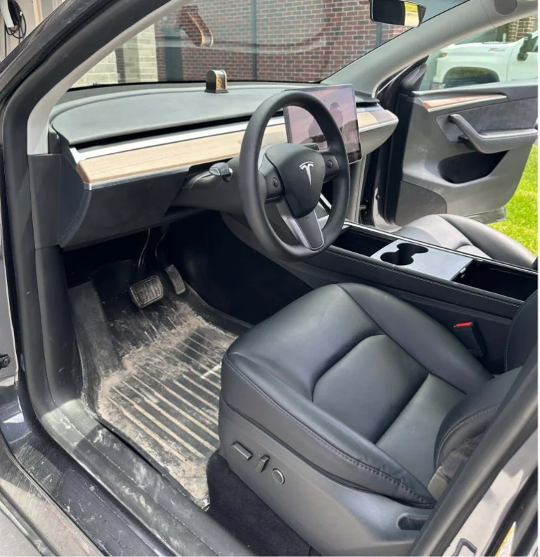 Before: muddy floor mat and dusty driver's area in a Tesla