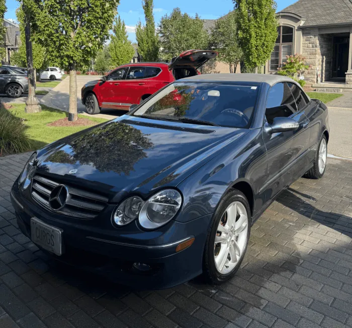 Blue Mercedes-Benz CLK convertible with glossy paint reflecting the trees after an exterior detail